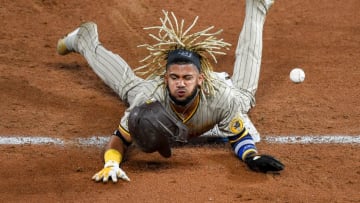 DENVER, CO - AUGUST 28: Fernando Tatis Jr. #42 of the San Diego Padres reacts after being hit by the ball on the pickoff attempt after sliding safely into third base with a sixth inning steal against the Colorado Rockies at Coors Field on August 28, 2020 in Denver, Colorado. All players are wearing #42 in honor of Jackie Robinson Day. The day honoring Jackie Robinson, traditionally held on April 15, was rescheduled due to the COVID-19 pandemic. (Photo by Dustin Bradford/Getty Images)