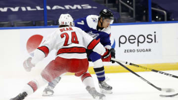 Feb 25, 2021; Tampa, Florida, USA; Tampa Bay Lightning right wing Mathieu Joseph (7) shoots as Carolina Hurricanes defenseman Jake Bean (24) defends during the third period at Amalie Arena. Mandatory Credit: Kim Klement-USA TODAY Sports