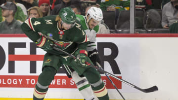 Oct 7, 2023; Saint Paul, Minnesota, USA; Minnesota Wild defense Jon Merrill (4) and Dallas Stars forward Logan Stankoven (11) battle for the puck during the second period at Xcel Energy Center. Mandatory Credit: Nick Wosika-USA TODAY Sports