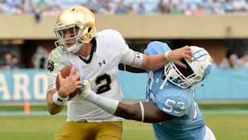 CHAPEL HILL, NC - OCTOBER 07: Ian Book #12 of the Notre Dame Fighting Irish stiff-arms Malik Carney #53 of the North Carolina Tar Heels during the game at Kenan Stadium on October 7, 2017 in Chapel Hill, North Carolina. Notre Dame won 33-10. (Photo by Grant Halverson/Getty Images)
