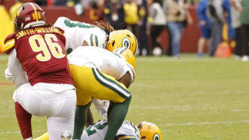 Oct 23, 2022; Landover, Maryland, USA; Green Bay Packers quarterback Aaron Rodgers (12) is helped up by teammates in front of Washington Commanders defensive end James Smith-Williams (96) after the final play of their game at FedExField. Mandatory Credit: Geoff Burke-USA TODAY Sports