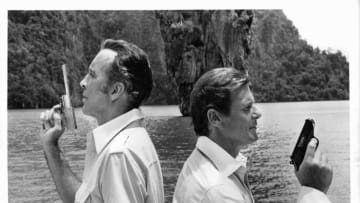 Christopher Lee back to back with Roger Moore, each holding a gun in the air in a scene from the film 'The Man With The Golden Gun', 1974. (Photo by United Artists/Getty Images)
