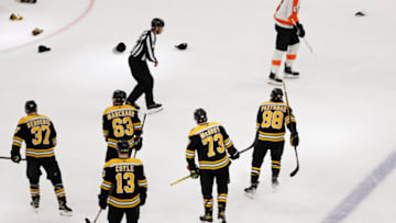 Jan 13, 2022; Boston, Massachusetts, USA; Hats litter the ice as Boston Bruins right wing David Pastrnak (88) skates towards the bench with center Patrice Bergeron (37), left wing Brad Marchand (63), center Charlie Coyle (13) and defenseman Charlie McAvoy (73) after scoring his third goal of the game as Philadelphia Flyers defenseman Travis Sanheim (6) passes by during the second period at TD Garden. Mandatory Credit: Winslow Townson-USA TODAY Sports