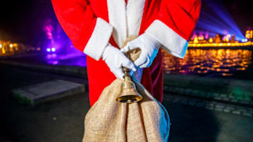 BERLIN, GERMANY - NOVEMBER 28: A Santa holds a bell and a bag of gifts as Santas gather for the Christmas General Assembly in the Tierpark Berlin zoo on November 28, 2021 in Berlin, Germany. The Berlin Santa Claus Headquarters (Berliner Weihnachtsmannzentrale) prepare for a busy Christmas season despite the coronavirus pandemic, making sure that all the outfits, gift bags and of course beards are in top shape for the holidays. (Photo by Omer Messinger/Getty Images)