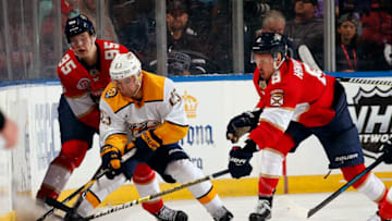 SUNRISE, FL - FEBRUARY 1: Rocco Grimaldi #23 of the Nashville Predators digs the puck out from the boards against Henrik Borgstrom #95 and teammate Jayce Hawryluk #8 of the Florida Panthers at the BB&T Center on February 1, 2019 in Sunrise, Florida. (Photo by Eliot J. Schechter/NHLI via Getty Images)