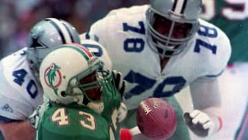 Miami Dolphin running back Terry Kirby (43) loses the ball while being brought down by Dallas Cowboys Brock Marion (31) Leon Lett (78) and Bill Bates (40) during first quarter action 25 November 1993 in Texas. The Cowboys recovered the ball. (Photo by PAUL BUCK / AFP) (Photo credit should read PAUL BUCK/AFP via Getty Images)