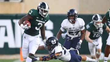 EAST LANSING, MI - AUGUST 31: LJ Scott #3 of the Michigan State Spartans tries to run through the tackle of Gaje Ferguson #23 of the Utah State Aggies at Spartan Stadium on August 31, 2018 in East Lansing, Michigan. (Photo by Gregory Shamus/Getty Images)