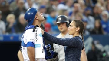 Luke Maile #21 of the Toronto Blue Jays is examined by head athletic trainer Nikki Huffman after taking a foul ball straight back off his mask in the fourth inning during MLB game action against the New York Yankees. (Photo by Tom Szczerbowski/Getty Images)