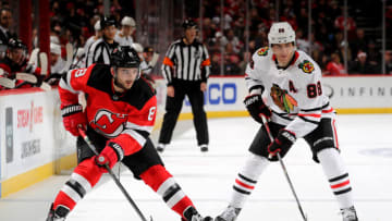 NEWARK, NEW JERSEY - DECEMBER 06: Will Butcher #8 of the New Jersey Devils passes the puck as Patrick Kane #88 of the Chicago Blackhawks defends at Prudential Center on December 06, 2019 in Newark, New Jersey.The Chicago Blackhawks defeated the New Jersey Devils 2-1 in a shootout. (Photo by Elsa/Getty Images)