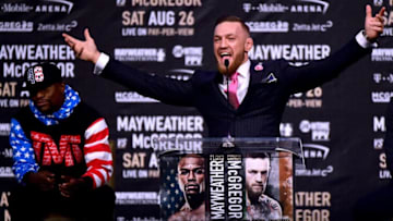 LOS ANGELES, CA - JULY 11: Conor McGregor speaks as Floyd Mayweather Jr. waits in the background during the Floyd Mayweather Jr. v Conor McGregor World Press Tour at Staples Center on July 11, 2017 in Los Angeles, California. (Photo by Harry How/Getty Images)
