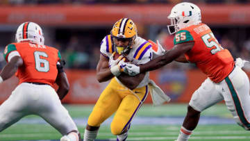 ARLINGTON, TX - SEPTEMBER 02: Nick Brossette #4 of the LSU Tigers carries the ball against Jhavonte Dean #6 of the Miami Hurricanes and Shaquille Quarterman #55 of the Miami Hurricanes in the first quarter of The AdvoCare Classic at AT&T Stadium on September 2, 2018 in Arlington, Texas. (Photo by Tom Pennington/Getty Images)