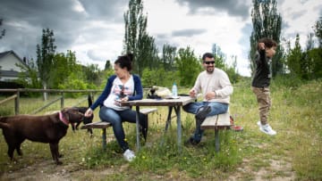 LAS MATAS, MADRID, SPAIN - MAY 13: Carolina resting with her husband Alfonso on a park picnic table feeds her dog, Shiva, as their kid Pablito plays jumping from the bench to the floor on May 13, 2020 in Las Matas, Madrid, Spain. As Spain eases its coronavirus lockdown measures, Carolina, who is five months pregnant, is still staying close to home as a precaution. She spends most of her time with her family or studying online to become a primary school teacher. The only exceptions to her home confinement are when she goes for a walk, to the supermarket, or for medical checkups. (Photo by Pablo Cuadra/Getty Image)