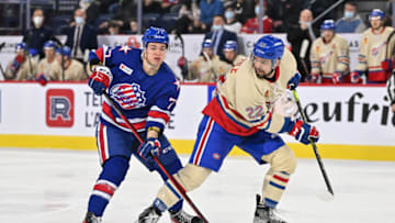 LAVAL, QC - APRIL 08: John Peterka #77 of the Rochester Americans and Alex Belzile #22 of the Laval Rocket skate against each other during the second period at Place Bell on April 8, 2022 in Laval, Canada. The Laval Rocket defeated the Rochester Americans 4-3 in overtime. (Photo by Minas Panagiotakis/Getty Images)