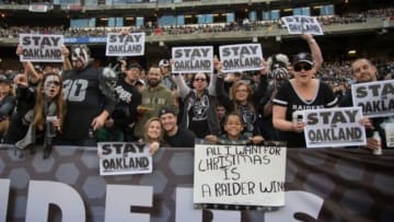 December 21, 2014; Oakland, CA, USA; Oakland Raiders fans hold "Stay in Oakland" signs during the third quarter against the Buffalo Bills at O.co Coliseum. The Raiders defeated the Bills 26-24. Mandatory Credit: Kyle Terada-USA TODAY Sports