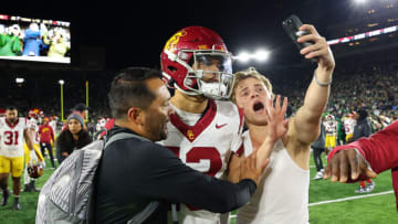 SOUTH BEND, INDIANA - OCTOBER 14: A fan takes a selfie with Caleb Williams #13 of the USC Trojans after the Notre Dame Fighting Irish defeated the USC Trojans and rushed the field at Notre Dame Stadium on October 14, 2023 in South Bend, Indiana. (Photo by Michael Reaves/Getty Images)