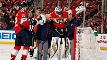 SUNRISE, FL - DECEMBER 4: Head Athletic Trainer Dave DiNapoli and Assistant Trainer Tommy Alva lift injured Goaltender Roberto Luongo