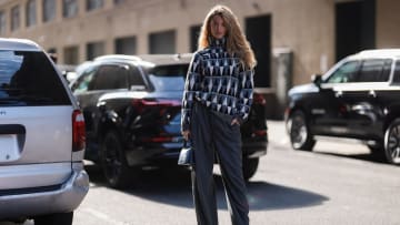 Kate Bock seen wearing blue white pullover, grey wide pants, Altuzarra blue bag and black boots, outside Altuzarra during New York Fashion Week on September 10, 2022 in New York City.