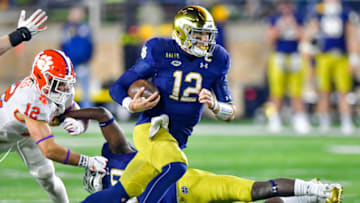 Nov 7, 2020; South Bend, Indiana, USA; Notre Dame Fighting Irish quarterback Ian Book (12) runs the ball in the second overtime period as Clemson Tigers safety Tyler Venables (12) pursues at Notre Dame Stadium. Notre Dame defeated Clemson 47-40 in two overtimes. Mandatory Credit: Matt Cashore-USA TODAY Sports