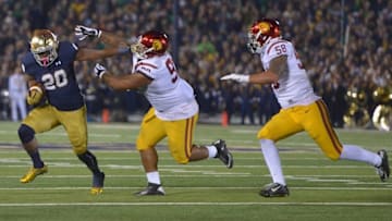 Oct 17, 2015; South Bend, IN, USA; Notre Dame Fighting Irish running back C.J. Prosise (20) is pursued by Southern California Trojans defensive tackle Antwaun Woods (99) and linebacker Osa Masina (58) at Notre Dame Stadium. Mandatory Credit: Kirby Lee-USA TODAY Sports