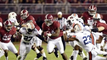 Nov 29, 2014; Tuscaloosa, AL, USA; Alabama Crimson Tide running back T.J. Yeldon (4) carries the ball between Auburn Tigers defensive back Robenson Therezie (27) and Johnathan Ford (23) in the second quarter at Bryant-Denny Stadium. Mandatory Credit: John David Mercer-USA TODAY Sports