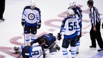 Oct 9, 2014; Glendale, AZ, USA; A trainer attends to Winnipeg Jets left wing Evander Kane (9) during the first period against the Arizona Coyotes at Gila River Arena. Mandatory Credit: Matt Kartozian-USA TODAY Sports