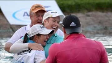 Apr 5, 2015; Rancho Mirage, CA, USA; Brittany Lincicome (middle right) hugs her caddie Missy Pederson after taking the leap into the pond with her father Tom Lincicome (background) and fiance