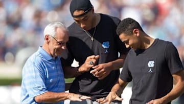 Sep 24, 2016; Chapel Hill, NC, USA; North Carolina Tar Heels basketball head coach Roy Williams compares rings with Brice Johnson and Marcus Paige during a timeout in the second quarter against the Pittsburgh Panthers at Kenan Memorial Stadium. Mandatory Credit: Jeremy Brevard-USA TODAY Sports