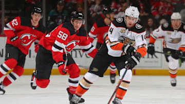 NEWARK, NJ - JANUARY 19: Adam Henrique #14 of the Anaheim Ducks plays the puck while being pursued by Kevin Rooney #58 of the New Jersey Devils during the game at Prudential Center on January 19, 2019 in Newark, New Jersey. (Photo by Andy Marlin/NHLI via Getty Images)