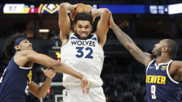 Minnesota Timberwolves center Karl-Anthony Towns grabs a rebound between Denver Nuggets players. Mandatory Credit: Bruce Kluckhohn-USA TODAY Sports