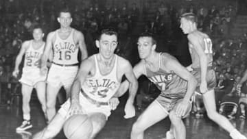 (Original Caption) Boston's Bob Cousy (14) tries to dribble past the guard of Milwaukee's Bob Harrison (7) during the third period of their game at the Garden tonight. Boston Celtics beat the Hawks, 95-85, in the opener of a double header. Other players in the photo include, Lew Hitch (12) of the Hawks, and Jack Nichols (16), of the Celtics.