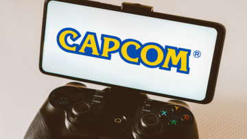 BRAZIL - 2023/08/14: In this photo illustration, the Capcom logo is seen displayed on a smartphone screen and connected to a gaming joystick. (Photo Illustration by Rafael Henrique/SOPA Images/LightRocket via Getty Images)