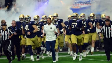 Jan 1, 2022; Glendale, Arizona, USA; Notre Dame Fighting Irish head coach Marcus Freeman leads players on the field against the Oklahoma State Cowboys during the first half of the 2022 Fiesta Bowl at State Farm Stadium. Mandatory Credit: Joe Camporeale-USA TODAY Sports