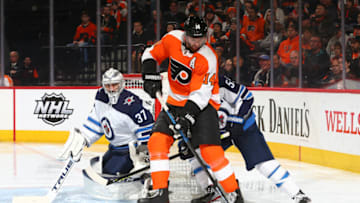 PHILADELPHIA, PA - FEBRUARY 22: Sean Couturier #14 of the Philadelphia Flyers controls the puck against Mark Scheifele #55 and Connor Hellebuyck #37 of the Winnipeg Jets in the third period at the Wells Fargo Center on February 22, 2020 in Philadelphia, Pennsylvania. The Flyers defeated the Jets 4-2. (Photo by Mitchell Leff/Getty Images)