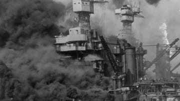 A small boat rescues sailors from the USS 'West Virginia' after she had suffered a hit in the Japanese attack on Pearl Harbor. The USS Tennessee (BB-43) is inboard of the sunken battleship. (Photo by Fox Photos/Getty Images)
