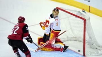 Feb 12, 2016; Glendale, AZ, USA; Arizona Coyotes right wing Shane Doan (not pictured) scores a goal on Calgary Flames goalie Jonas Hiller (1) as center Tyler Gaudet (32) looks on during the first period at Gila River Arena. Mandatory Credit: Matt Kartozian-USA TODAY Sports
