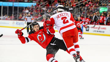 NEWARK, NJ - JANUARY 22: Detroit Red Wings defensman Joe Hicketts (2) knocks down New Jersey Devils center Nico Hischier (13) during the first period of the National Hockey League game between the New Jersey Devils and the Detroit Red Wings on January 22, 2018, at the Prudential Center in Newark, NJ. (Photo by Rich Graessle/Icon Sportswire via Getty Images)