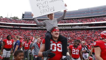 ATHENS, GA - NOVEMBER 26: Tate Ratledge #69 of the Georgia Bulldogs holds up Kirby Smarts son Andrew at the conclusion of the Georgia Bulldogs 37-14 victory over the Georgia Tech Yellow Jackets at Sanford Stadium on November 26, 2022 in Athens, Georgia. (Photo by Todd Kirkland/Getty Images)