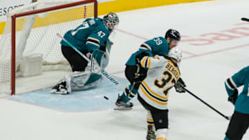 Feb 26, 2022; San Jose, California, USA; Boston Bruins center Patrice Bergeron (37) shoots and scores against San Jose Sharks center Logan Couture (39) and goaltender James Reimer (47) during the third period at SAP Center at San Jose. Mandatory Credit: John Hefti-USA TODAY Sports