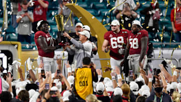 MIAMI GARDENS, FLORIDA - JANUARY 11: Head coach Nick Saban and Alex Leatherwood #70 of the Alabama Crimson Tide hold up the CFP National Championship Trophy on the trophy presentation stage with Mac Jones #10, Landon Dickerson #69, Christian Barmore #58, and DeVonta Smith #6 after the College Football Playoff National Championship football game against the Ohio State Buckeyes at Hard Rock Stadium on January 11, 2021 in Miami Gardens, Florida. The Alabama Crimson Tide defeated the Ohio State Buckeyes 52-24. (Photo by Alika Jenner/Getty Images)