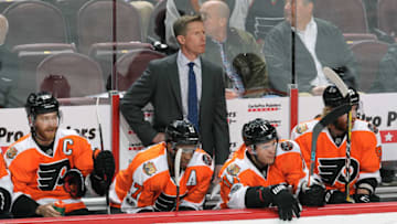 PHILADELPHIA, PA - MARCH 13: Head Coach Dave Hakstol of the Philadelphia Flyers follows the play on the ice behind Claude Giroux