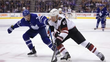 Feb 11, 2020; Toronto, Ontario, CAN; Arizona Coyotes forward Lawson Crouse (67) battles for control of the puck with Toronto Maple Leafs defenseman Justin Holl (3) during the second period at Scotiabank Arena. Mandatory Credit: John E. Sokolowski-USA TODAY Sports