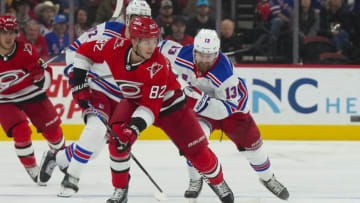 Mar 23, 2023; Raleigh, North Carolina, USA; Carolina Hurricanes center Jesperi Kotkaniemi (82) skates with the puck past New York Rangers left wing Alexis Lafrenière (13) during the first period at PNC Arena. Mandatory Credit: James Guillory-USA TODAY Sports