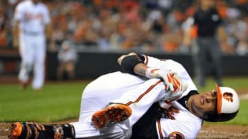 Aug 11, 2014; Baltimore, MD, USA; Baltimore Orioles third baseman Manny Machado (13) goes down with a knee injury after striking out in the third inning against the New York Yankees at Oriole Park at Camden Yards. Mandatory Credit: Joy R. Absalon-USA TODAY Sports