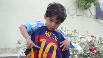 QUETTA, PAKISTAN - MAY 03: Murtaza Ahmedi, a five year old Afghan boy who wears a jersey signed by Messi, poses as he holds another jersey from Messi in Quetta of Balochistan province, a South-Western city in Pakistan on May 3, 2016. A boy from Ghazni province of Afghanistan became famous on social media in the world after wearing a plastic bag shirt resembling the uniform of international football star Lionel Messi. Messi had also expressed his wish to meet Murtaza Ahmedi. Parents of Murtaza Ahmedi moved him to Quetta from Afghanistan hence they worried about kidnapping, Mr. Wahid Ahmedi, a relative of the boy said. They also appealed to football federations and both Afghanistan and Pakistan government for making arrangements of meeting between Lionel Messi and Murtaza Ahmedi. (Photo by Mazhar Chandio/Anadolu Agency/Getty Images)