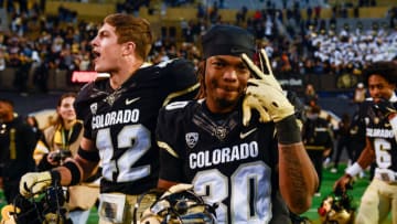 BOULDER, CO - NOVEMBER 20: Safety Curtis Appleton II #30 and safety Trevor Woods #42 of the Colorado Buffaloes on the field as players celebrate a 20-17 win over the Washington Huskies at Folsom Field on November 20, 2021 in Boulder, Colorado. (Photo by Dustin Bradford/Getty Images)