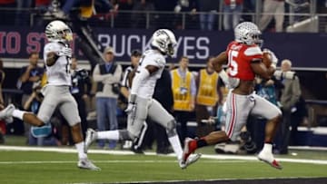 Jan 12, 2015; Arlington, TX, USA; Ohio State Buckeyes running back Ezekiel Elliott (15) scores a touchdown in front of Oregon Ducks defensive back Chris Seisay (12) during the first quarter in the 2015 CFP National Championship Game at AT&T Stadium. Mandatory Credit: Tim Heitman-USA TODAY Sports