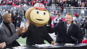 Nov 23, 2019; Columbus, OH, USA; ESPN Gameday host Lee Corso puts on a Brutus Buckeye head on while sitting between former Buckeyes Eddie George and Kirk Herbstreit before the game between the Ohio State Buckeyes and Penn State Nittany Lions at Ohio Stadium. Mandatory Credit: Greg Bartram-USA TODAY Sports