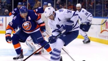 Oct 21, 2014; Uniondale, NY, USA; Toronto Maple Leafs right wing Joffrey Lupul (19) plays the puck in front of New York Islanders right wing Kyle Okposo (21) during the first period at Nassau Veterans Memorial Coliseum. Mandatory Credit: Brad Penner-USA TODAY Sports