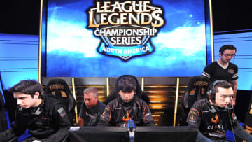 Team Curse players Christian 'IWillDominate' Rivera (L), Joedat 'Voyboy' Esfahani (C) and David 'Cop' Roberson (R) prepare for the start of a match as two broadcast technicians (background) prepare the live video feed, during the League of Legends North American Championship Series Spring round robin competition, at the MBS Media Campus in Manhattan Beach, California February 22, 2014. League of Legends is the king of the hot trend in videogame play as a spectator sport, complete with sold-out stadiums and fans camping all night for tickets to matches. AFP PHOTO / ROBYN BECK (Photo credit should read ROBYN BECK/AFP/Getty Images)