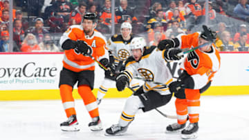 PHILADELPHIA, PA - NOVEMBER 20: Craig Smith #12 of the Boston Bruins battles for the puck with Ivan Provorov #9 and Justin Braun #61 of the Philadelphia Flyers in the third period at the Wells Fargo Center on November 20, 2021 in Philadelphia, Pennsylvania. The Boston Bruins defeated the Philadelphia Flyers 5-2. (Photo by Mitchell Leff/Getty Images)